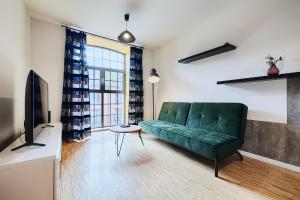 a living room with a green couch and a tv at Loft Green by LookAp in Łódź