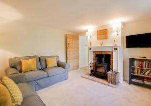 sala de estar con sofá y chimenea en Barn Meadow Cottage, en Yoxford