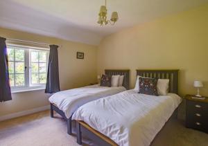 1 dormitorio con 2 camas y ventana en Barn Meadow Cottage, en Yoxford