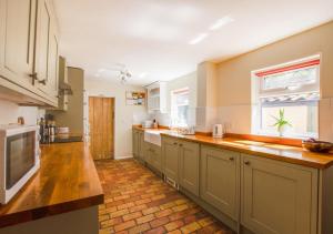 cocina grande con encimeras de madera y ventana en Barn Meadow Cottage, en Yoxford