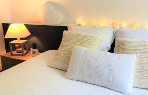 een bed met witte kussens en een tafel met een lamp bij "BELLEVUE" Magnifique appartement vue sur mer et face à Nausicàa in Boulogne-sur-Mer