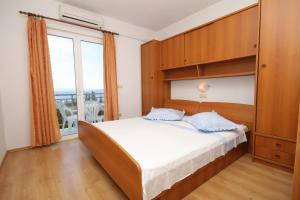 1 dormitorio con cama y ventana grande en Apartments and rooms with parking space Brela, Makarska - 6895 en Brela