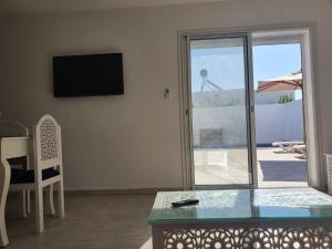 ein Wohnzimmer mit einem Tisch und einer Glasschiebetür in der Unterkunft Villa de luxe avec piscine sans vis à vis Midoun in Aghīr