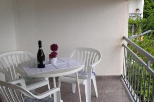 uma mesa branca com uma garrafa de vinho e duas cadeiras em Apartments by the sea Podaca, Makarska - 6745 em Podaca