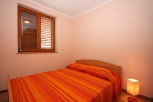 um quarto com uma cama com um cobertor laranja e uma janela em Seaside holiday house Tisno, Murter - 5094 em Tisno