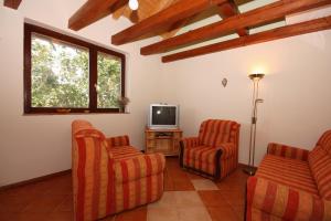 uma sala de estar com duas cadeiras e uma televisão em Seaside holiday house Tisno, Murter - 5094 em Tisno
