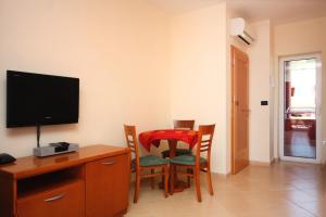 een kamer met een tafel en stoelen en een televisie bij Seaside apartments with a swimming pool Barbat, Rab - 4980 in Rab