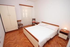 a bedroom with a white bed and a wooden floor at Holiday house with a parking space Sali, Dugi otok - 8138 in Sali