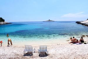 a group of people sitting on a beach at Rooms by the sea Hvar - 8785 in Hvar