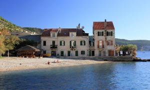 ein großes Gebäude am Strand neben dem Wasser in der Unterkunft Apartments by the sea Komiza, Vis - 9703 in Komiža