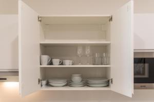 un armario de cocina blanco con platos y vasos. en Vienna City Apartment, en Viena