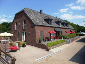 a brick building with red umbrellas in front of it at Gocher Berghof Ferienwohnungen Langanke in Goch
