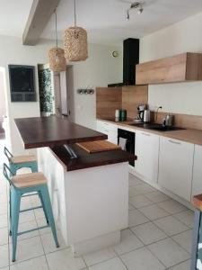 a kitchen with white cabinets and a wooden counter top at Jolie maison de ville avec un extérieur au calme - Les Dragons de la Chamoiserie NIORT in Niort