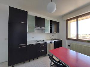 una cocina con armarios negros y una mesa roja. en Appartamento Codroipo Centrale, en Codroipo