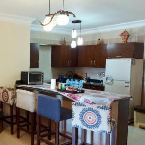 a kitchen with a counter with chairs and a refrigerator at Cheerful Villa - Romance Resort in Ain Sokhna