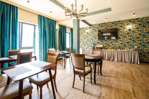 uma sala de jantar com mesas e cadeiras e uma televisão em Hotel GENI Kazbegi em Kazbegi