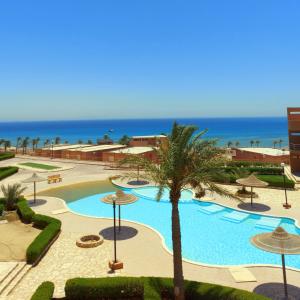 a swimming pool with a palm tree and the ocean at Cheerful Villa - Romance Resort in Ain Sokhna