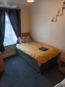 a small bedroom with a bed with a window at Strides Hotel in Blackpool