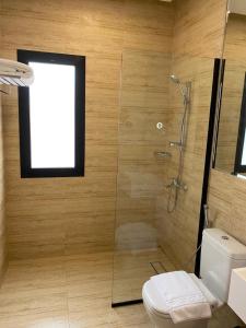 uma casa de banho com um chuveiro, um WC e uma janela. em Half Moon Al Khobar Resort em Half Moon Bay