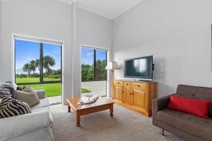 a living room with a couch and a tv at Sea View Cottage - Ruakaka Holiday Cottage in Ruakaka