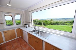 een keuken met een wastafel en een groot raam bij VILLA&MAR LANGRE BEACH in Langre