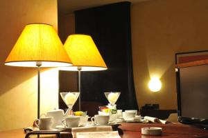 dos lámparas en una mesa con tazas y vasos en Hotel Parco, en Castelvetro Piacentino