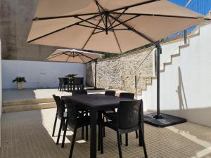 Una mesa con sillas y una sombrilla en un patio. en Apartamentos Castelo, en Póvoa de Varzim