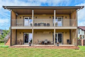 a house with a balcony and a table and chairs at Vila „Prie tvenkinio“ in Palanga