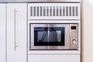 a microwave oven in a white cabinet at Double Ensuite in Central Forest Row in Forest Row