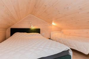 a bedroom with two beds in a wooden room at Vila „Prie tvenkinio“ in Palanga