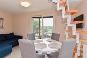 a living room with a table and chairs and a spiral staircase at Vila „Prie tvenkinio“ in Palanga