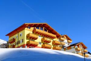 alpsrental Apartments Freja Obertauern في اوبرتاورن: مبنى على رأس منحدر مغطى بالثلج