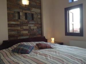 a bedroom with a brick wall and a bed with two pillows at Pilion Stone House in Áyios Vlásios