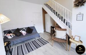 a living room with a blue couch and a staircase at Bee Stays - Pickmere House in Warrington