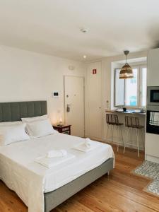 a bedroom with a large white bed and a kitchen at Concha Setúbal Miradouro in Setúbal