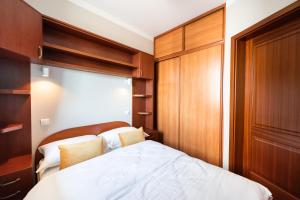 1 dormitorio con cama blanca y armarios de madera en Metro Wilanowska Homely Apartment, en Varsovia