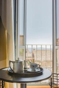 un tavolo con teiera e tazze su un tavolo vicino a una finestra di Hotel Priori Secret Garden a Perugia