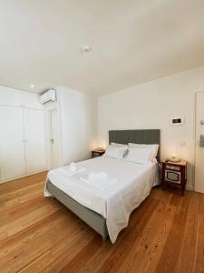 a bedroom with a large white bed and wooden floors at Concha Setúbal Miradouro in Setúbal