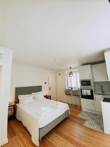 a bedroom with a large white bed and a kitchen at Concha Setúbal Miradouro in Setúbal