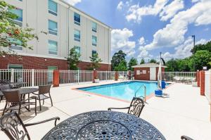 um pátio com uma mesa e cadeiras e uma piscina em Holiday Inn Express & Suites Baton Rouge East, an IHG Hotel em Baton Rouge