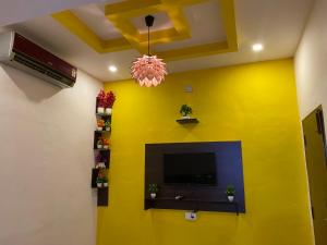 a living room with a yellow wall with a tv at Rock N riveR in Malpe