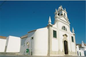Une grande église blanche avec une cloche au-dessus dans l'établissement Casa do Pátio em Alcantarilha - Algarve, à Alcantarilha