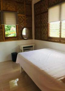 Schlafzimmer mit einem weißen Bett und einem Spiegel in der Unterkunft MIOKI HOMETEL in Batuan