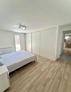 een witte slaapkamer met een bed en een houten vloer bij Appartement spacieux et moderne avec un extérieur in Ramatuelle