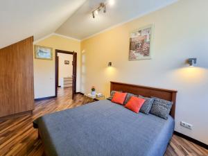 1 dormitorio con 1 cama con almohadas de color naranja y gris en Viesu māja Vētras, en Trenči