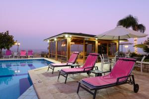 a group of pink chairs by a swimming pool at Rom Mansion in Rosh Pinna