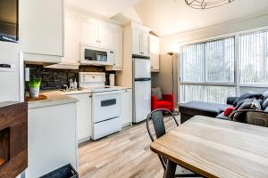 a kitchen and living room with white cabinets and a table at Le Villageois by Gestion ELITE in Mont-Tremblant