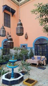 einen Innenhof mit einem blauen Brunnen vor einem Gebäude in der Unterkunft RIAD DAR KADER chambre saumon in Marrakesch