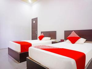 - 2 lits dans une chambre avec des draps rouges et blancs dans l'établissement OYO 91432 Dalle 5151 Jeneponto, à Pannara