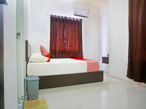 - une chambre avec un lit et un rideau rouge dans l'établissement OYO 91432 Dalle 5151 Jeneponto, à Pannara
